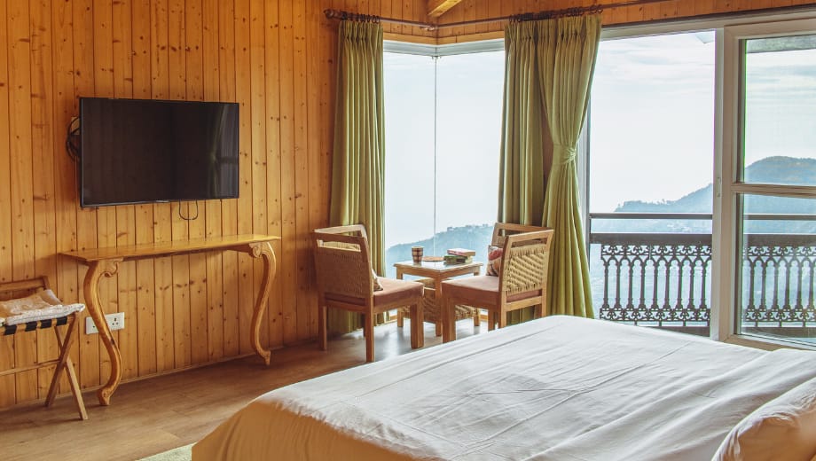 Modern bedroom with attached balcony offering panoramic landscape view